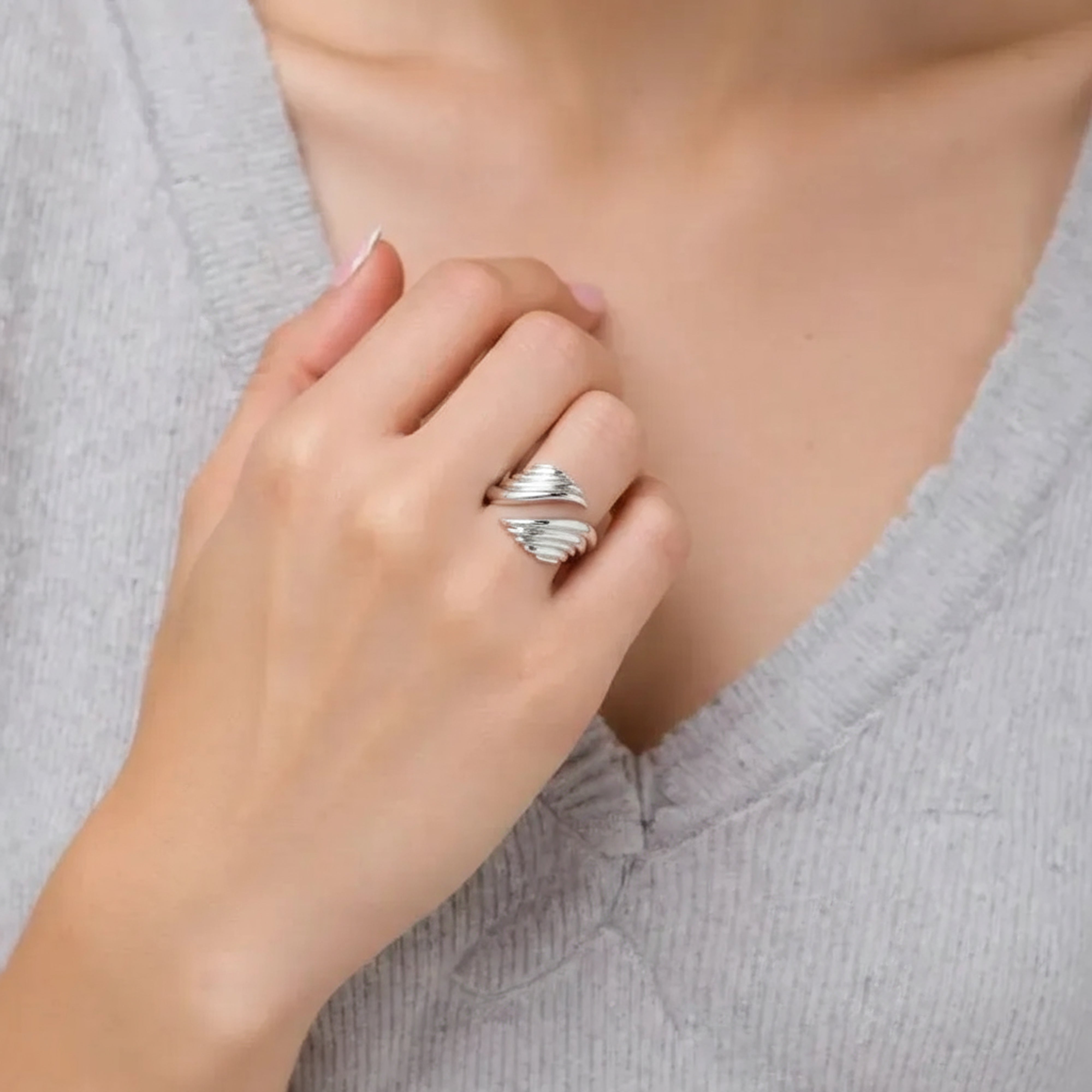 Bague aile d'ange en argent massif portée au doigt par une femme