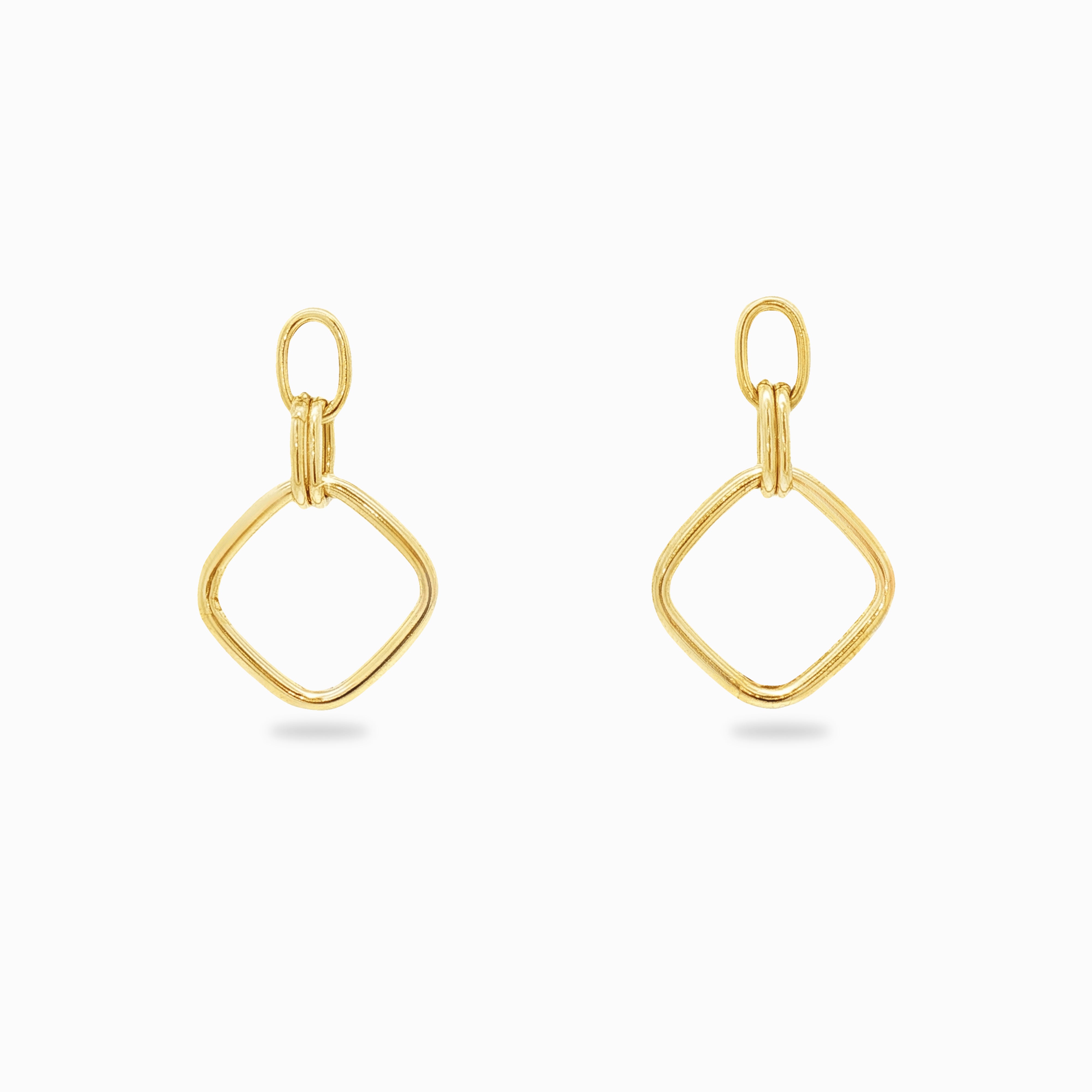 Boucles d'oreilles pendantes or de forme losange sur un fond blanc