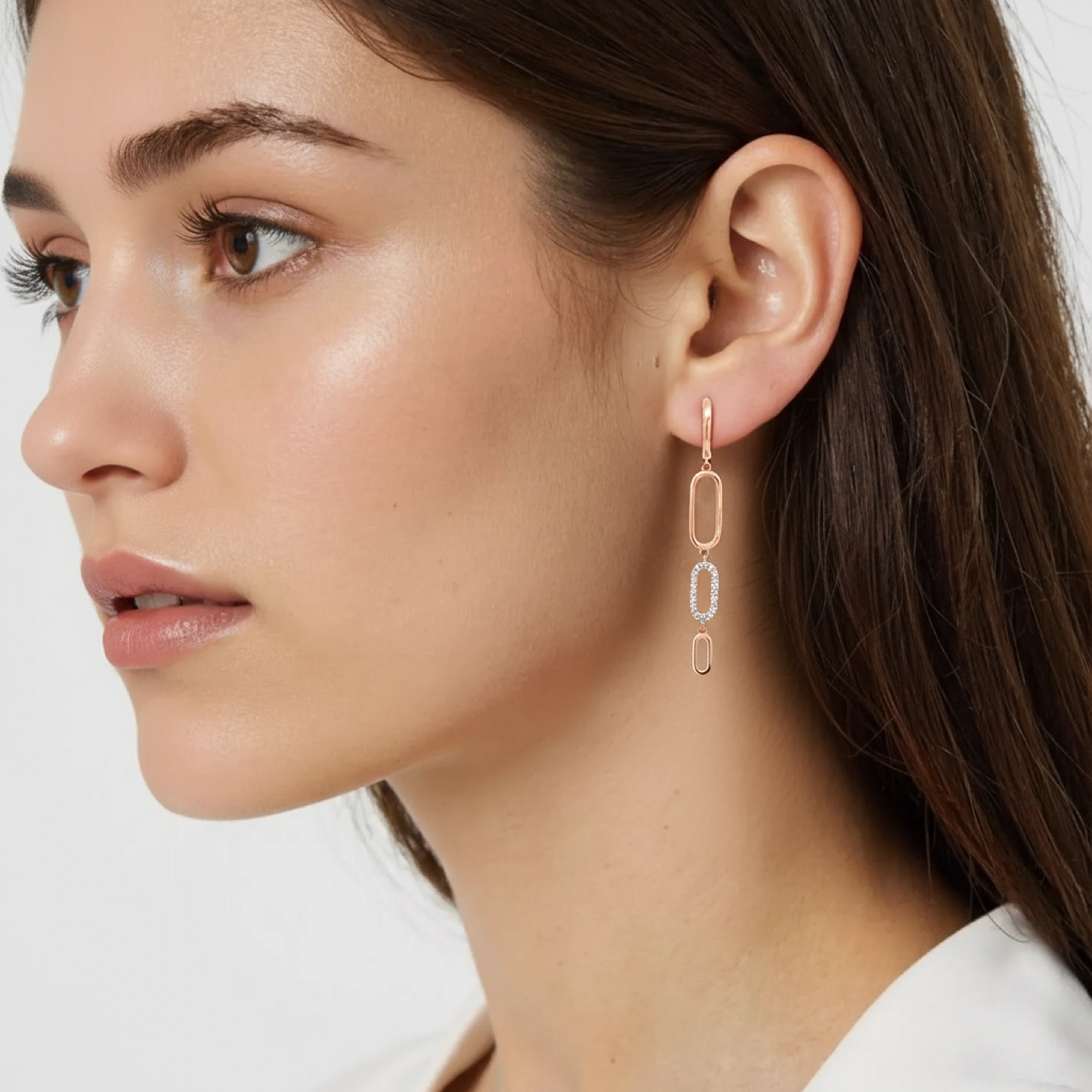 Femme porte une boucle d'oreille pendante en or rose avec des zircons