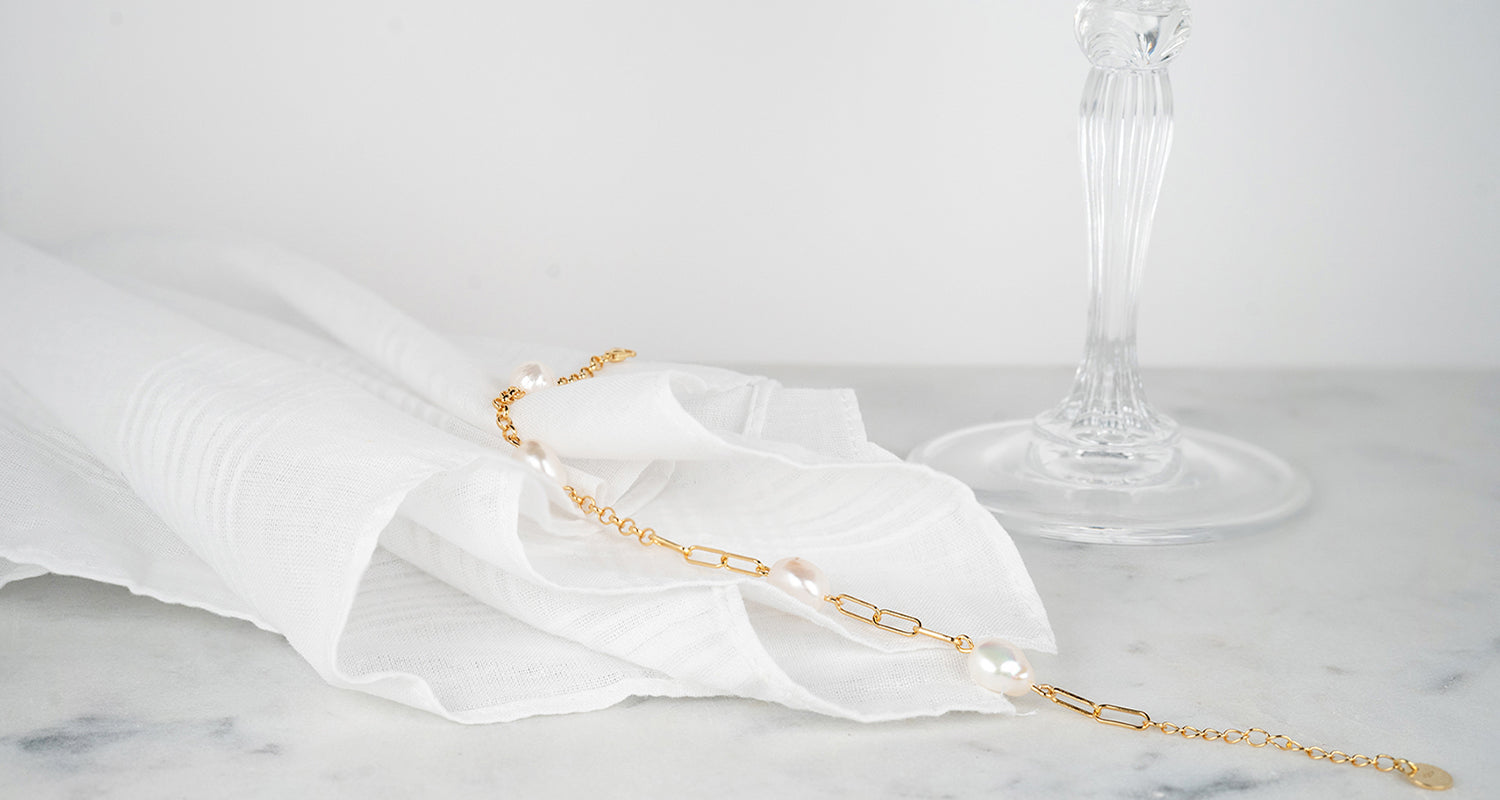 Bracciale a catena in oro giallo con perle su tessuto bianco