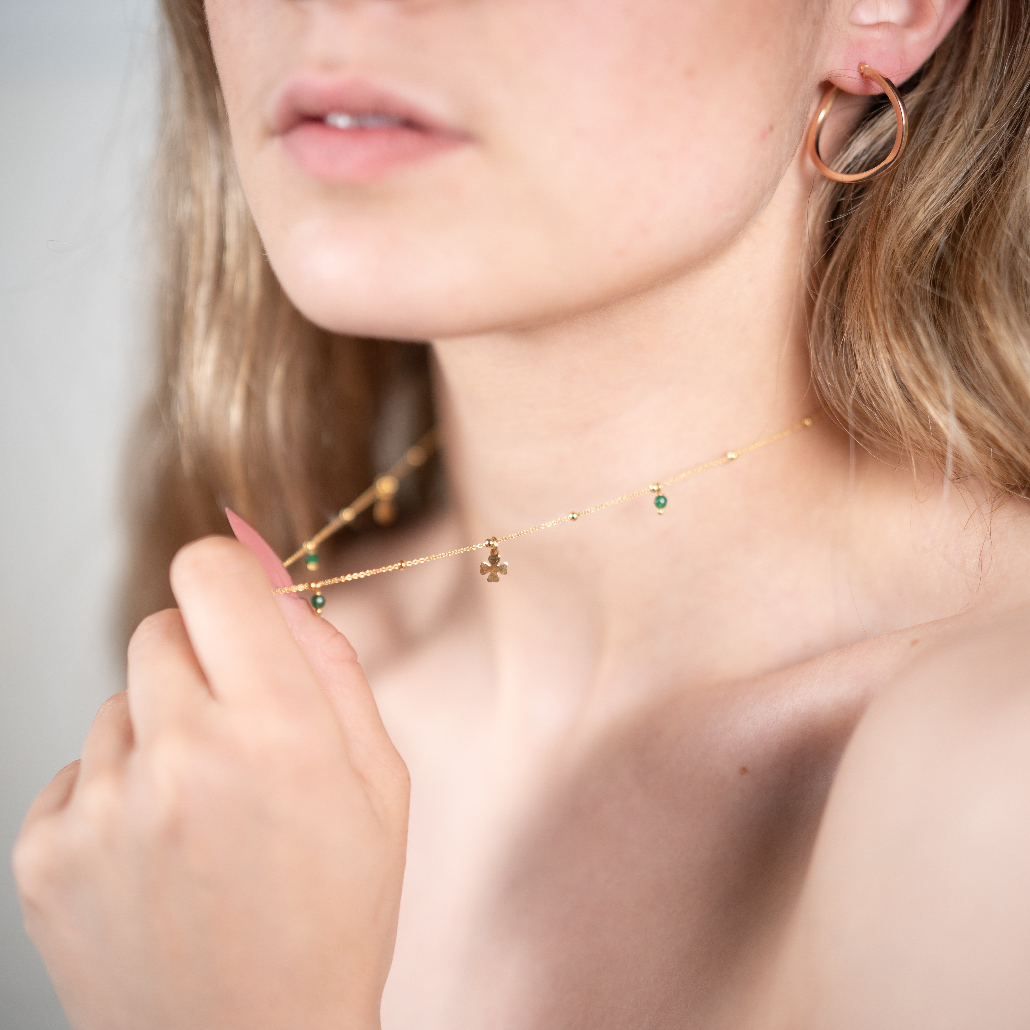 Collana di quarzo verde portafortuna in argento 925 con placcatura in oro giallo indossata da una donna con orecchini a cerchio