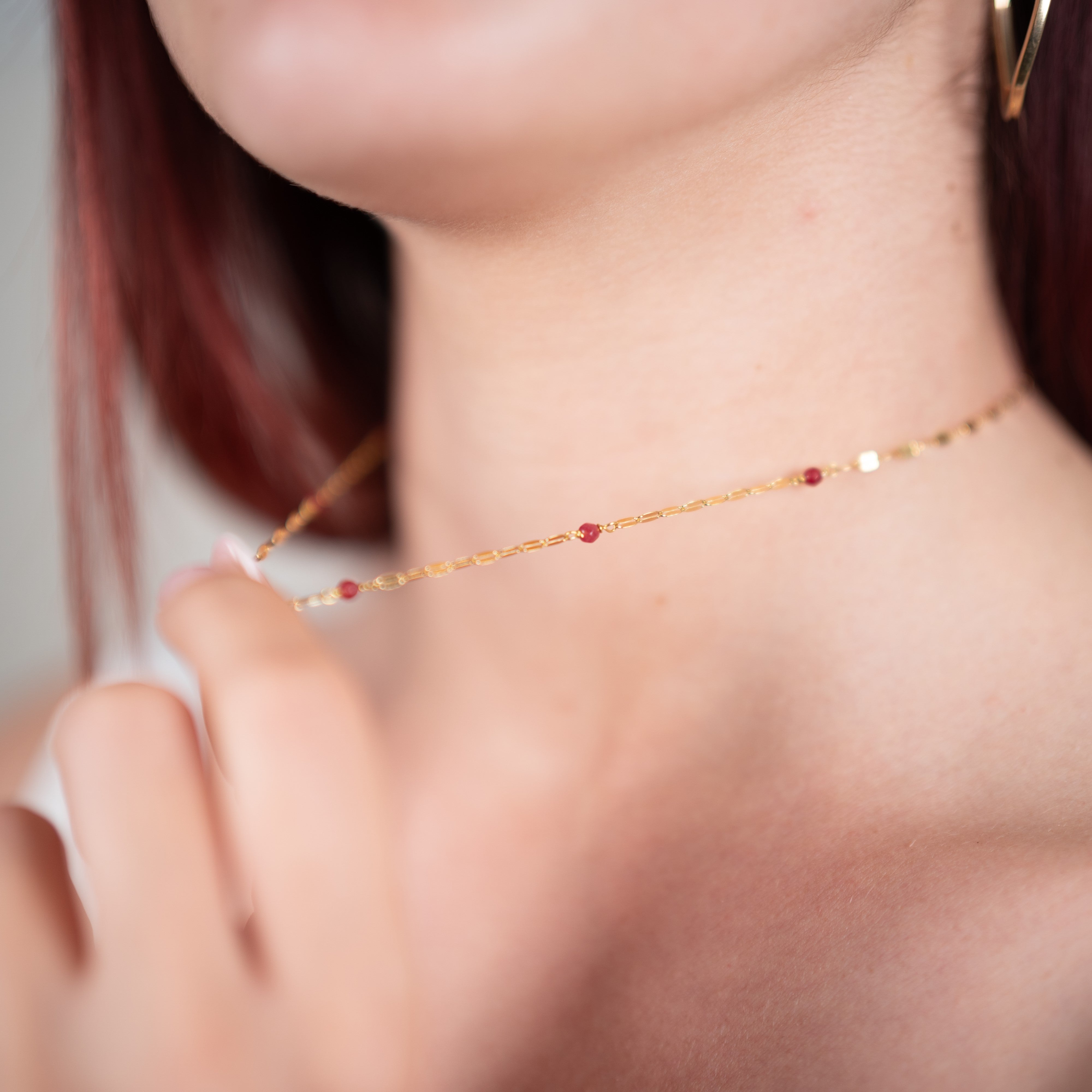 Collier à pendentifs quartz rouge en argent 925 plaqué or jaune et sa chaîne grain de café porté par une femme