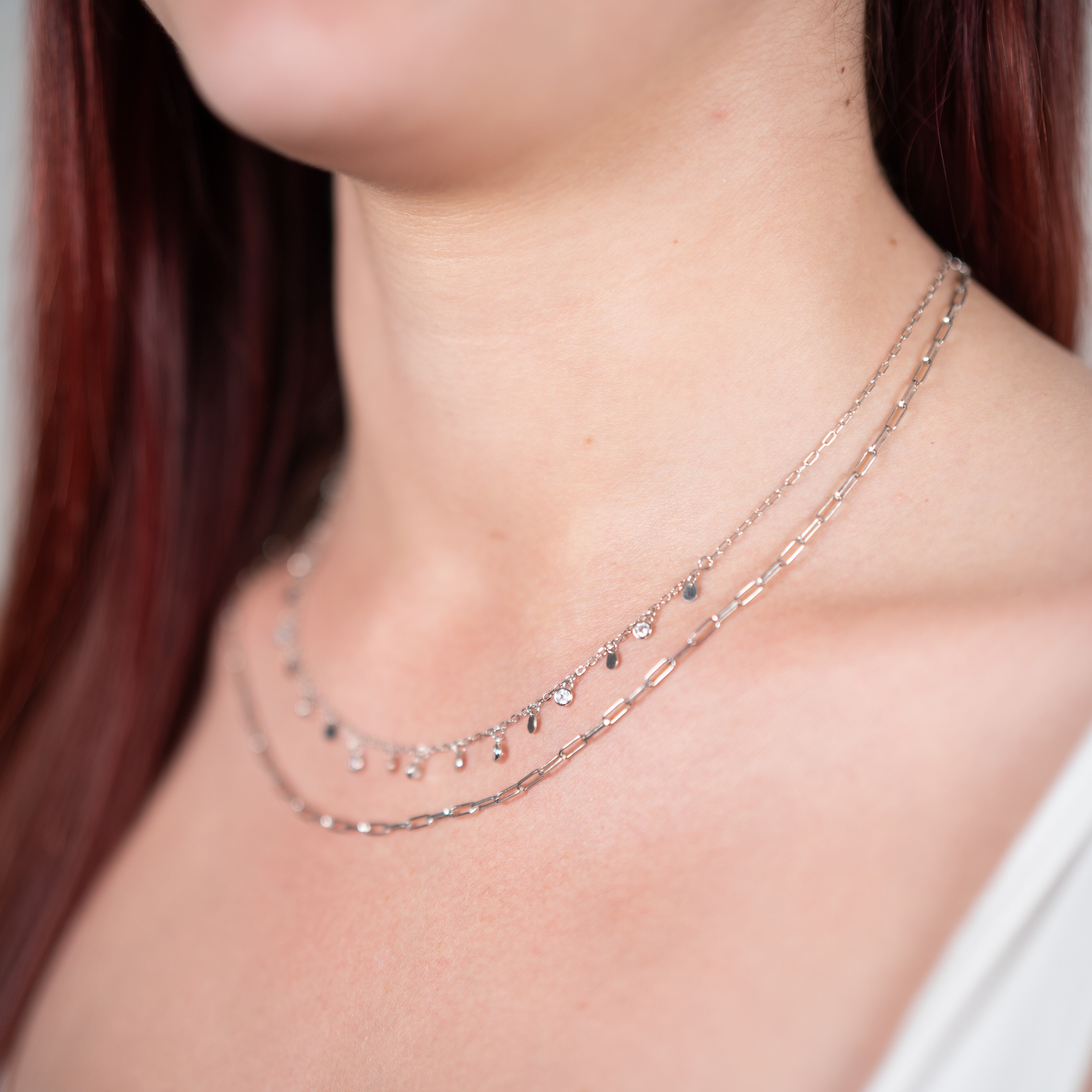 Zirconium chain necklace and rhodium-plated silver pendants worn by a woman
