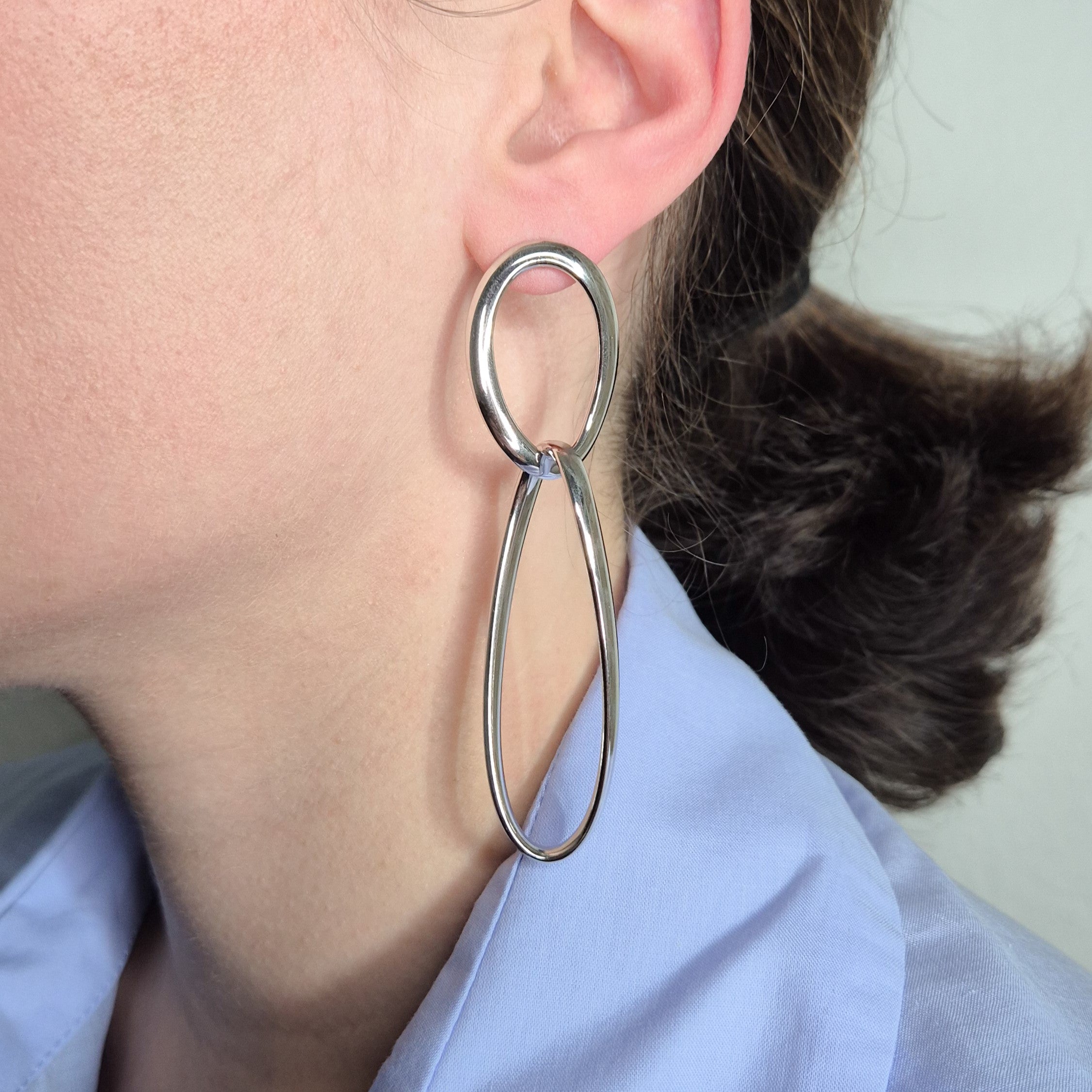 Femme portant des boucles d'oreilles longues pendantes en argent massif