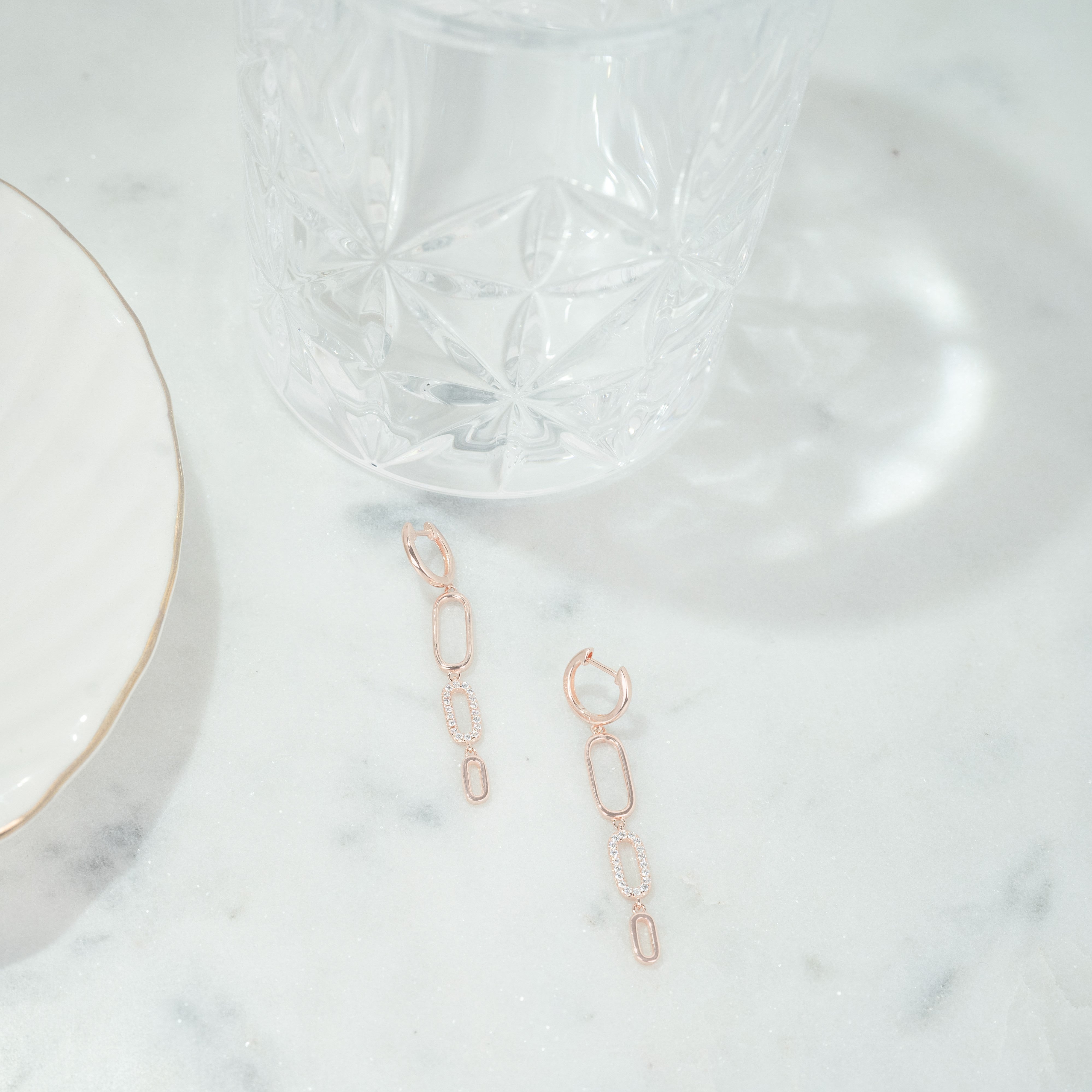 Long zirconium rose gold earrings set on marble