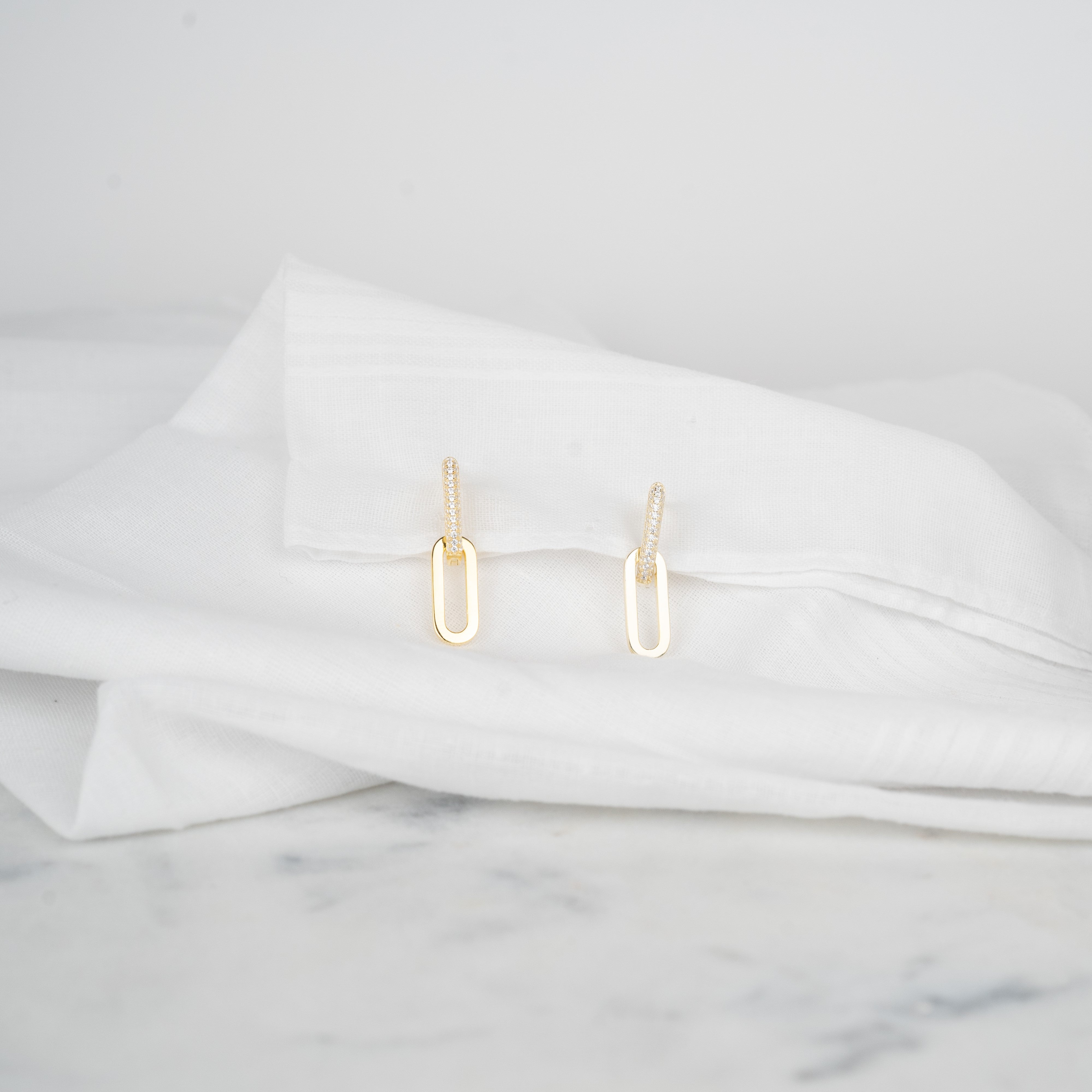 Modular zirconium pendant earrings on white fabric