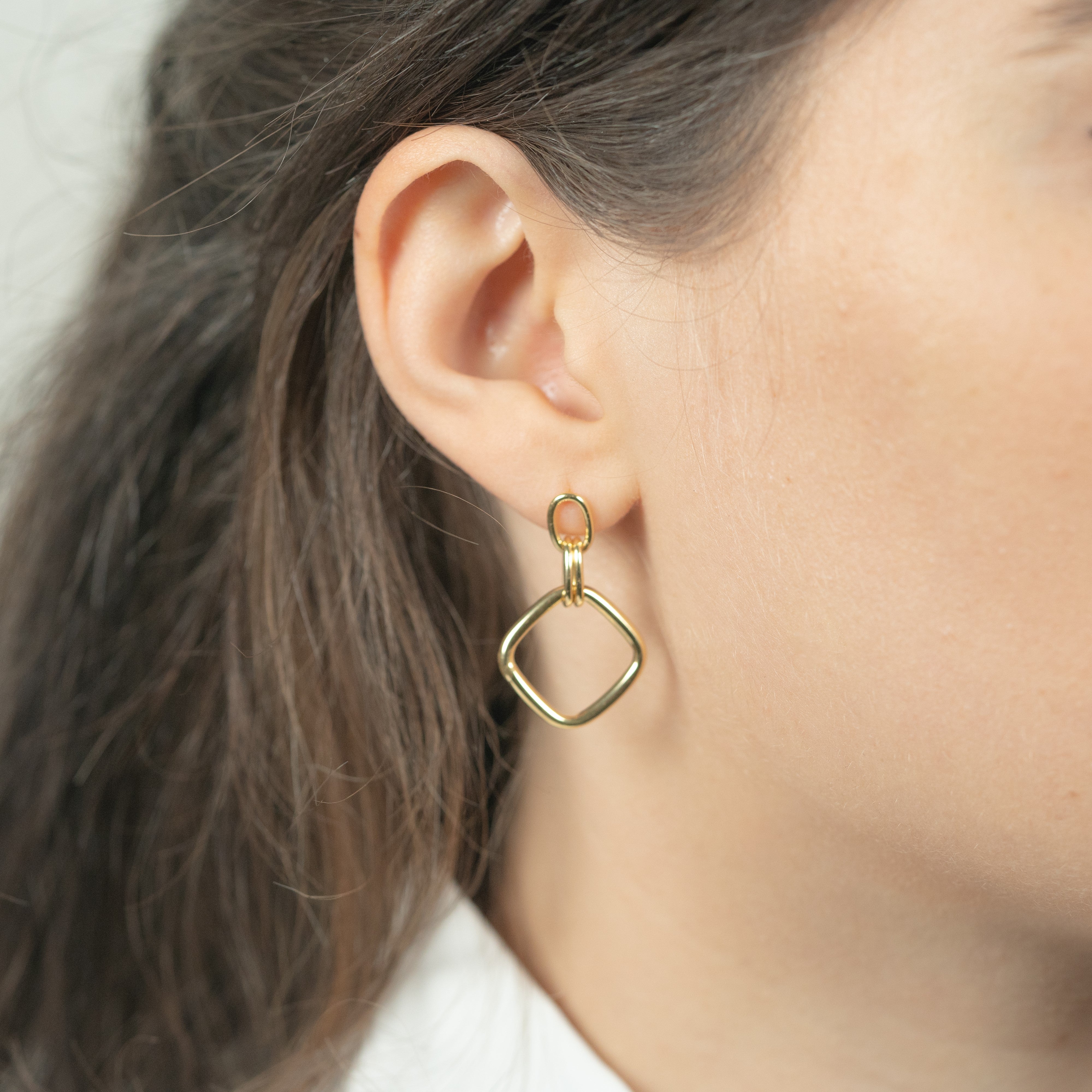 Boucles d'oreilles pendantes or losange en argent portées sur un modèle