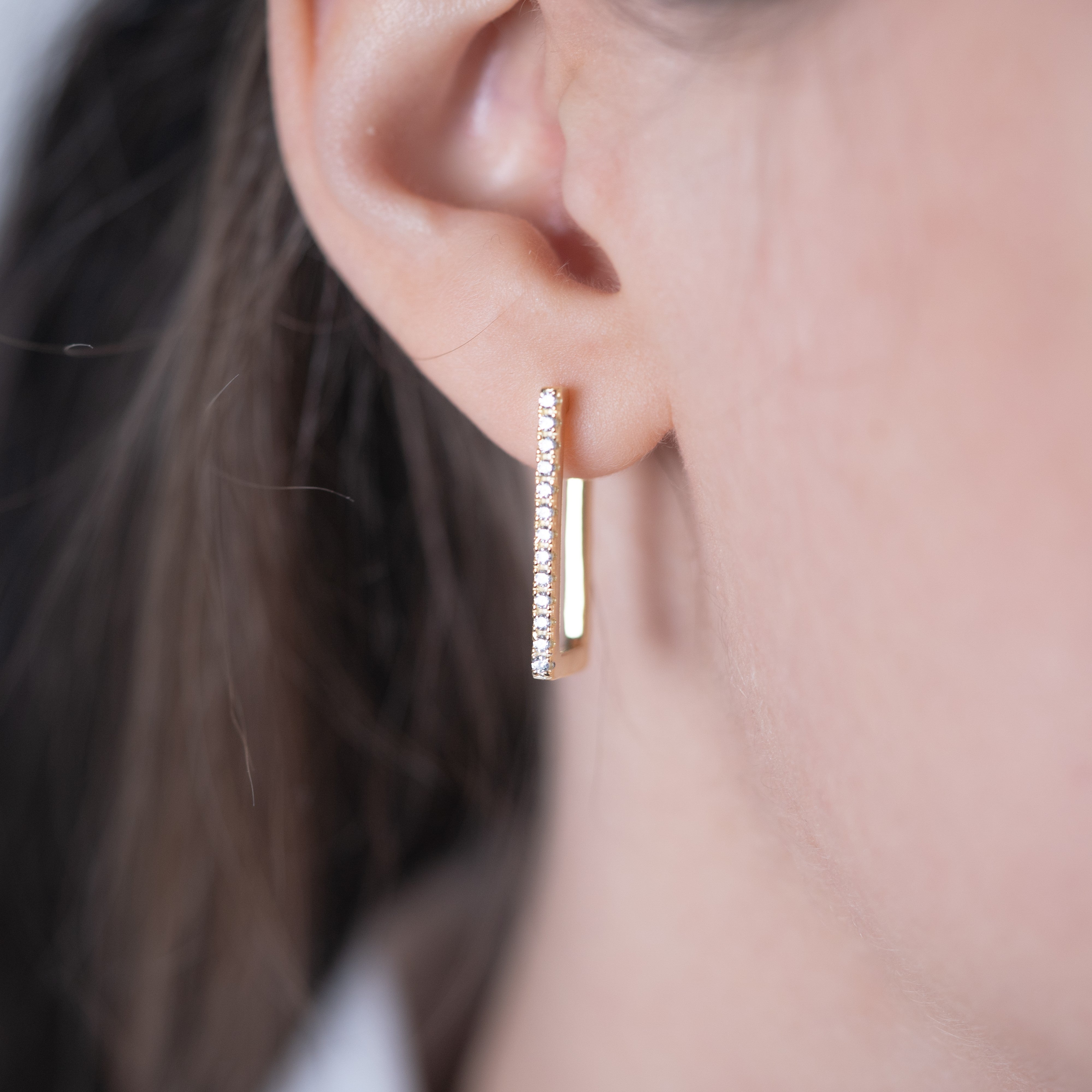 Boucles d'oreilles rectangulaires or portées sur un modèle