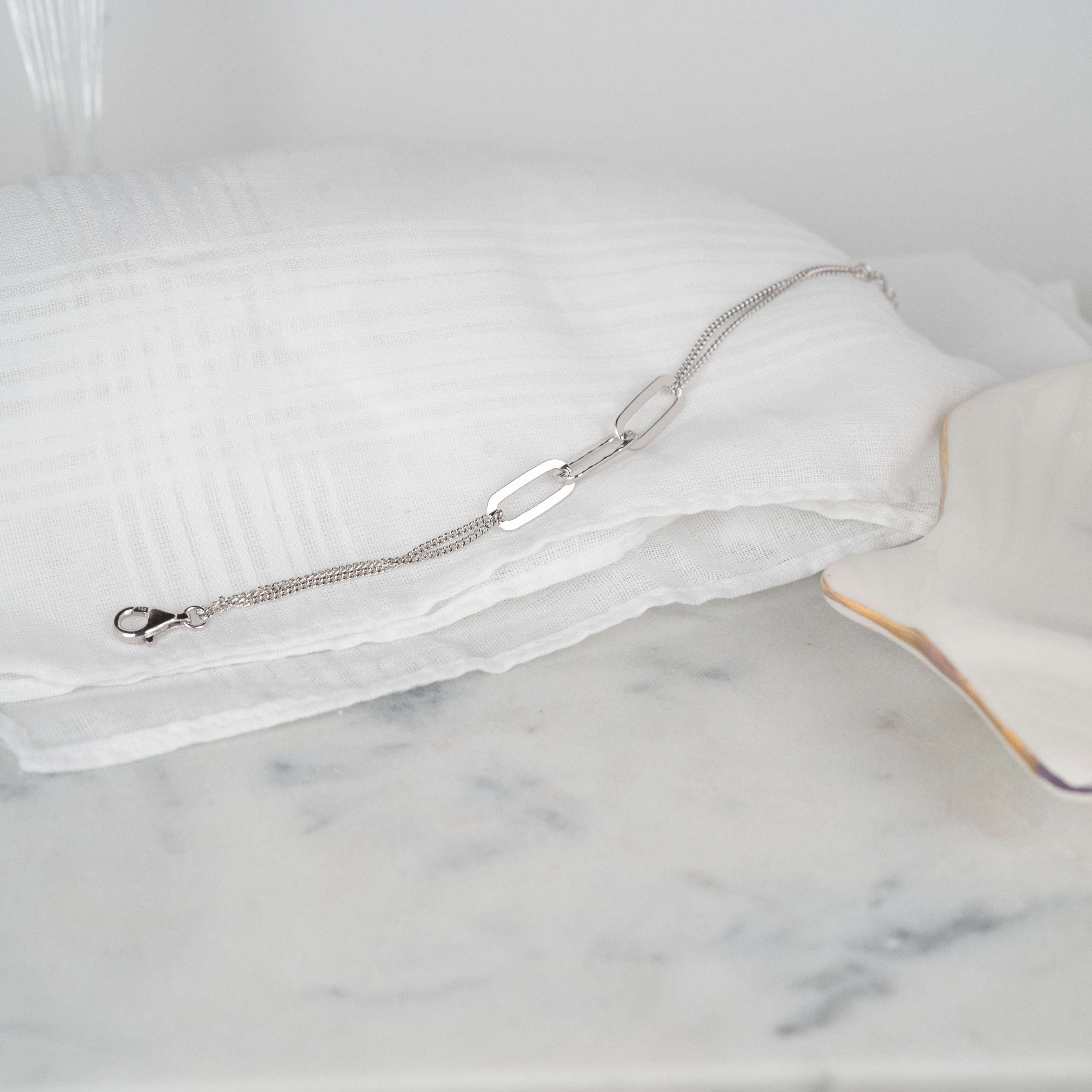 Solid silver link bracelet set on white fabric and marble