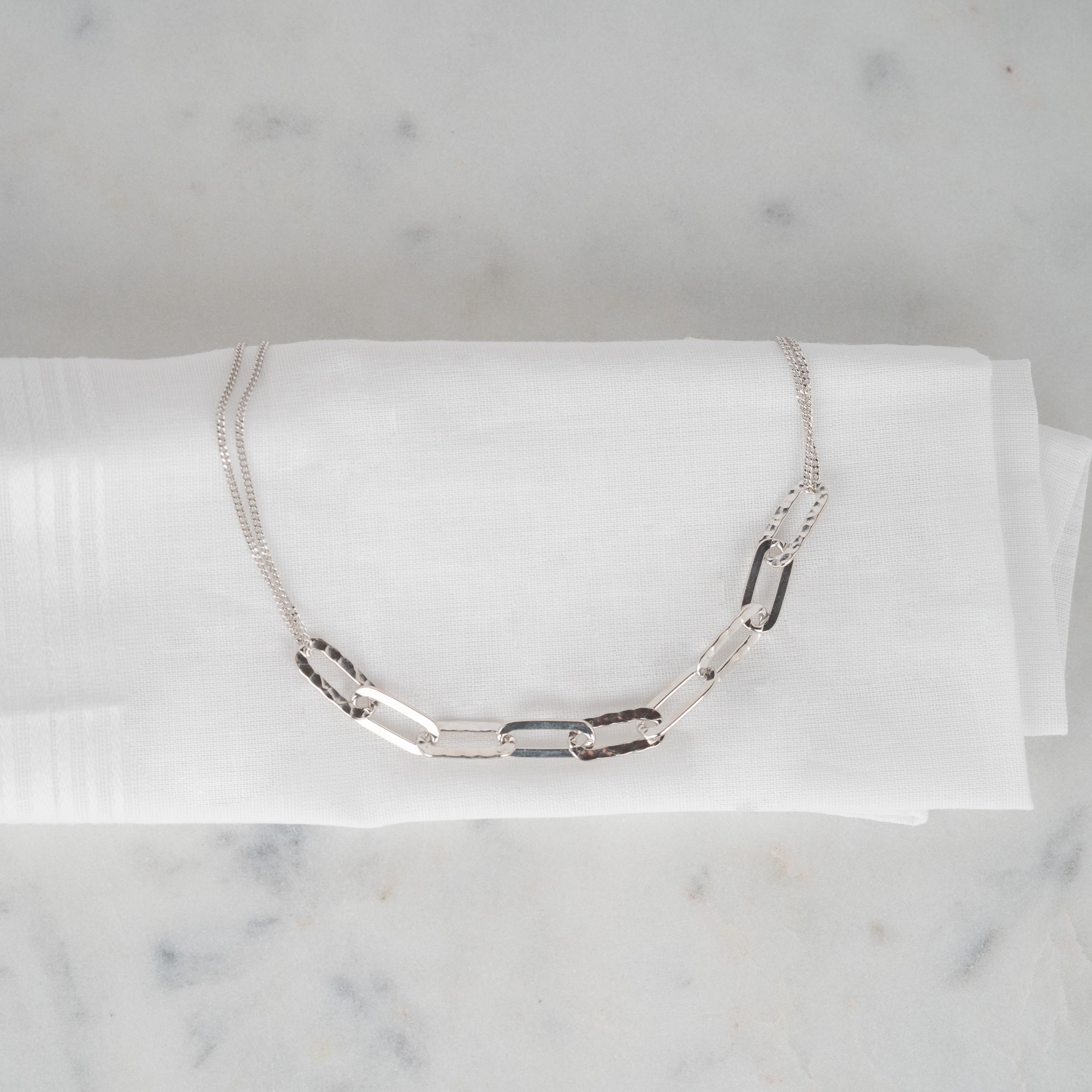 Gliederkette aus rhodiniertem 925er Silber, die auf einem weißen Stoff liegt