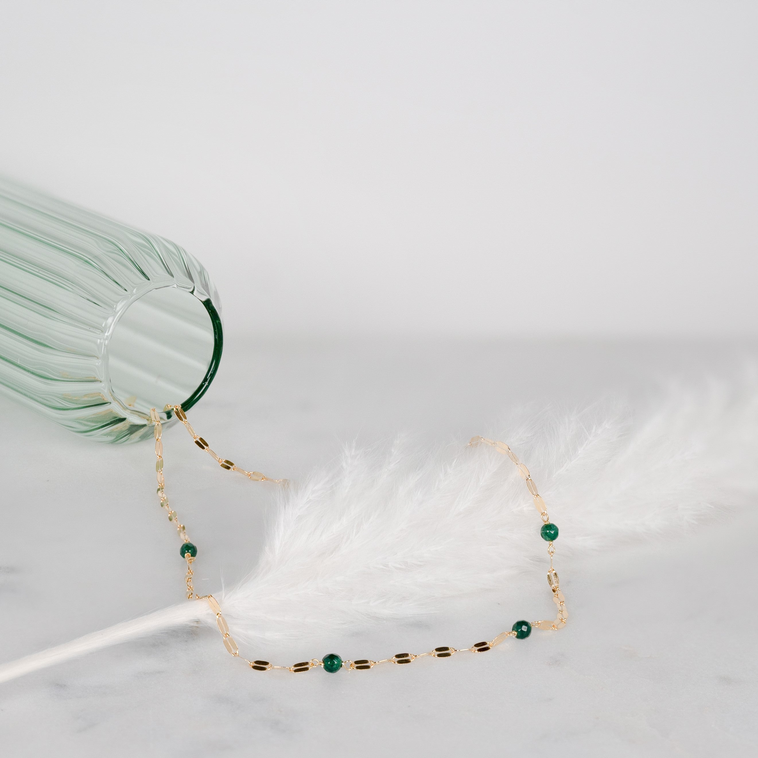 Green quartz necklace with yellow gold-plated silver and coffee bean chain on a white feather