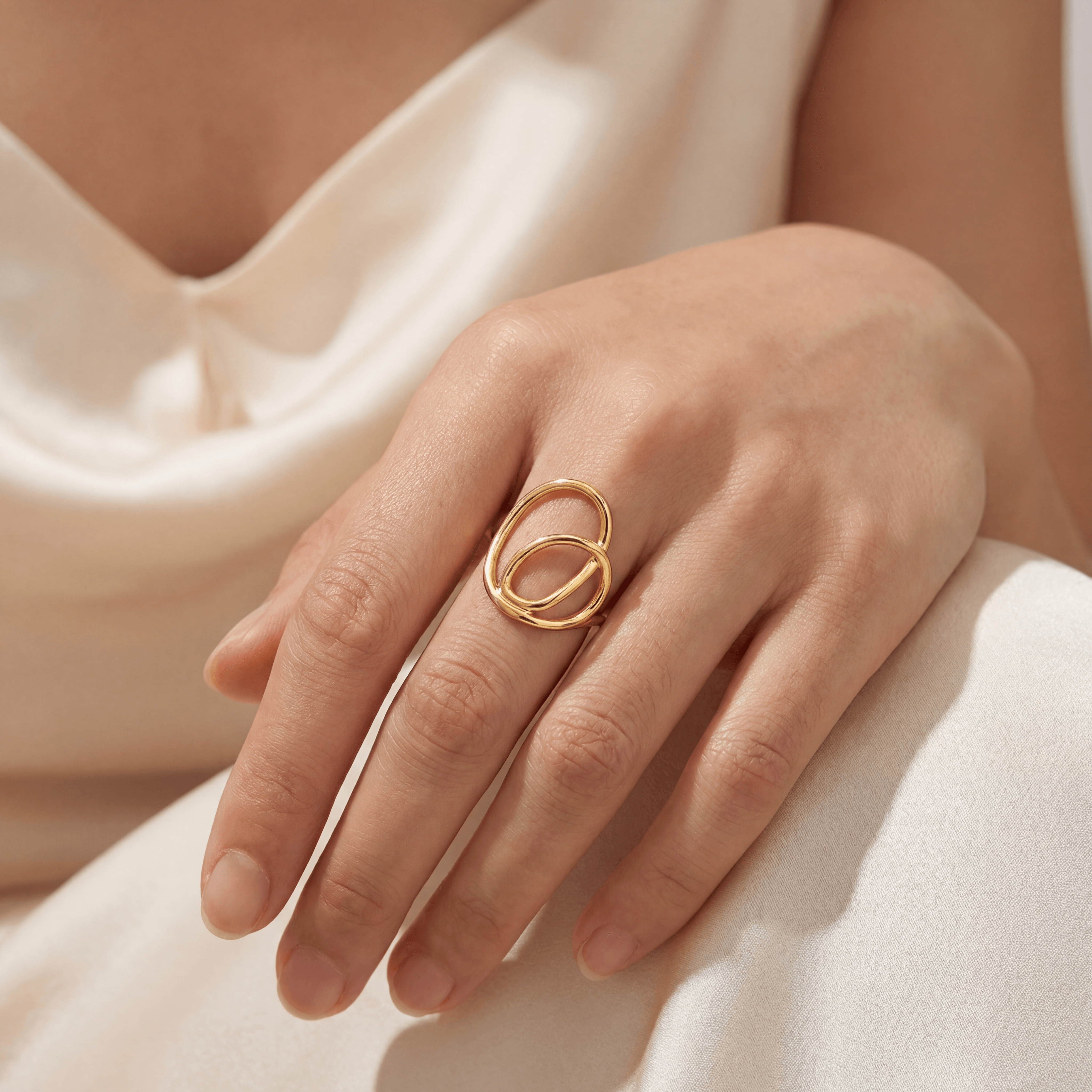 Bague entrelacée plaquée or jaune portée au doigt d'une main