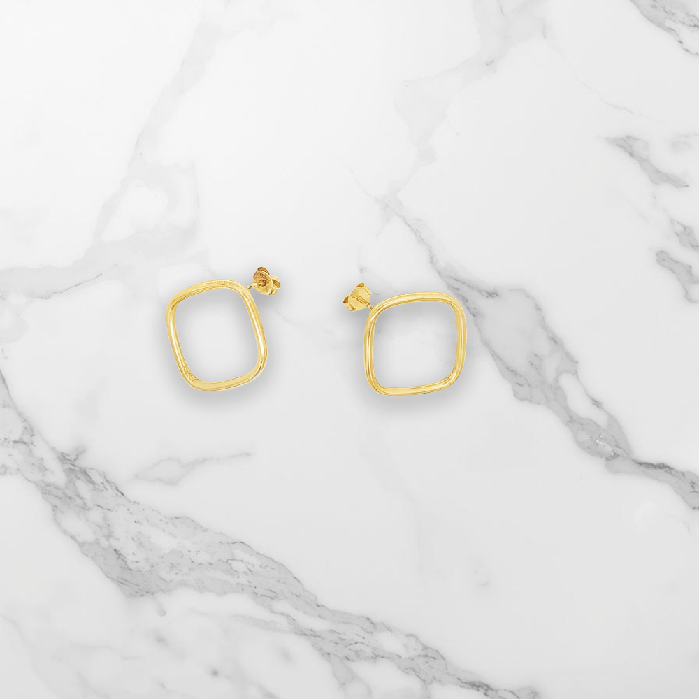Boucles d'oreilles carrées posées sur un marbre blanc