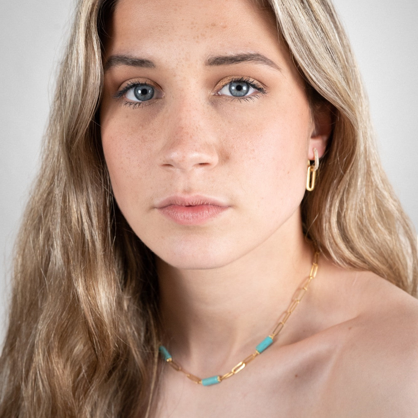 Boucles d'oreilles zirconium modulables portées sur une femme avec un collier turquoise