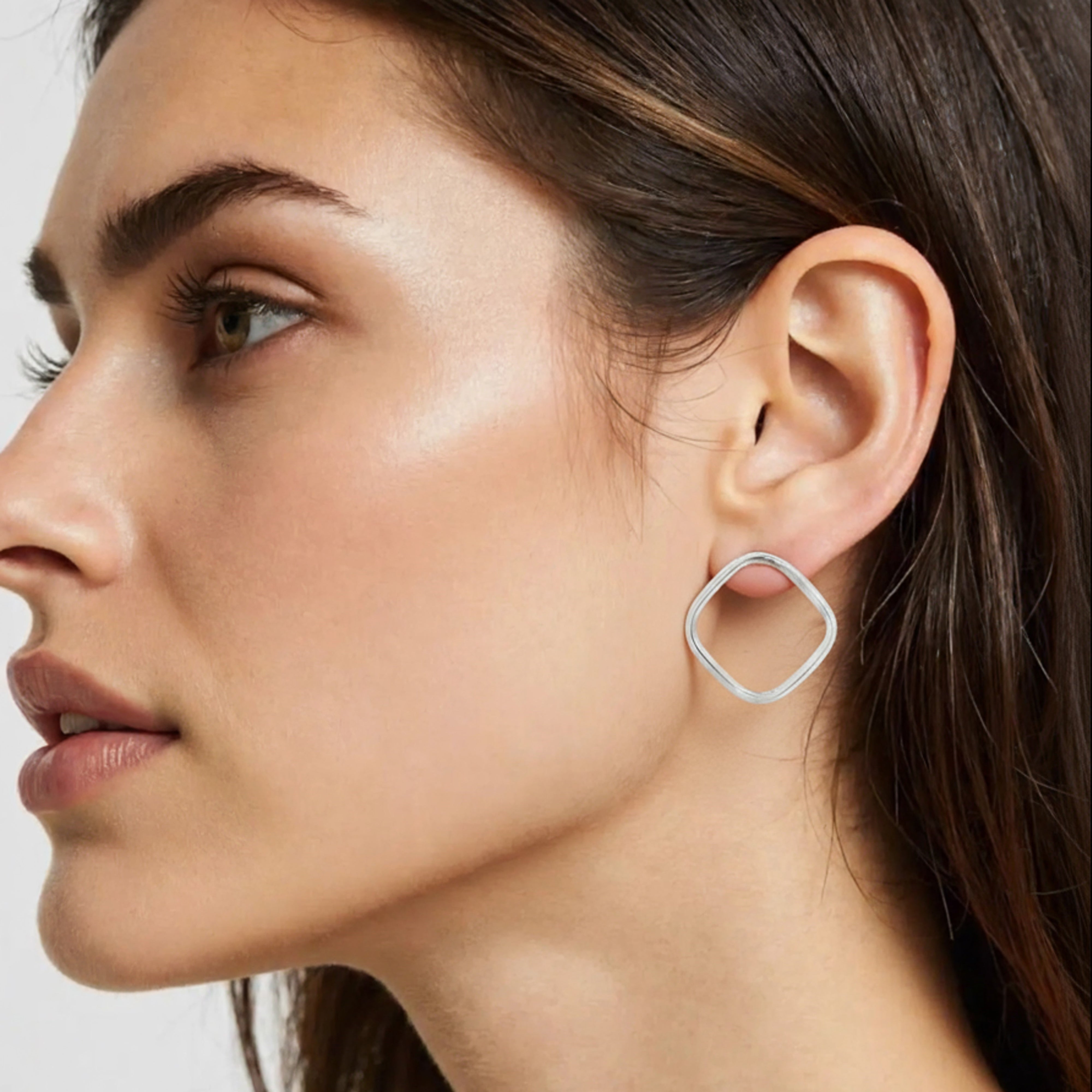 Une femme porte une boucle d'oreille carrée en argent massif