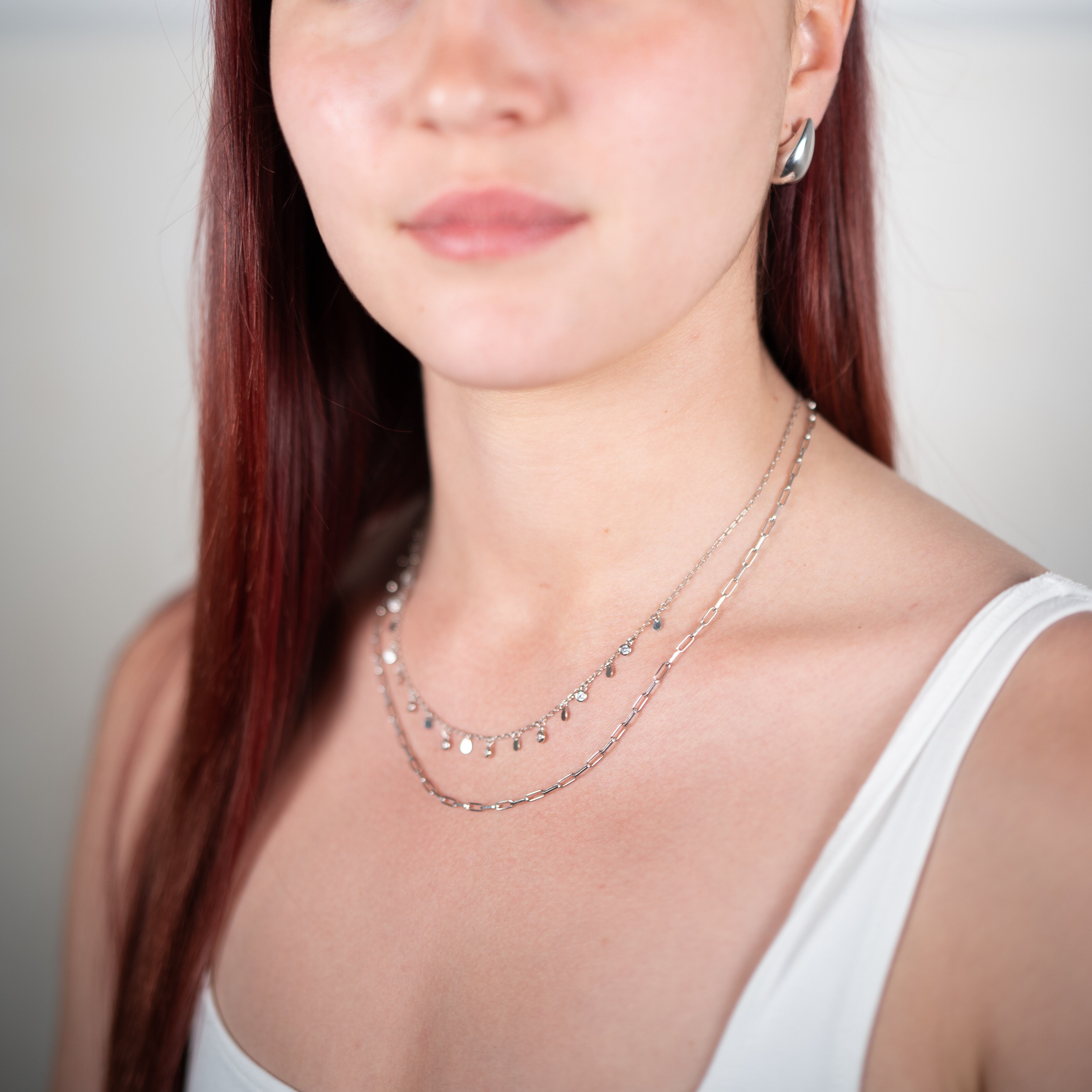 Silver drop earrings worn with a zirconium necklace