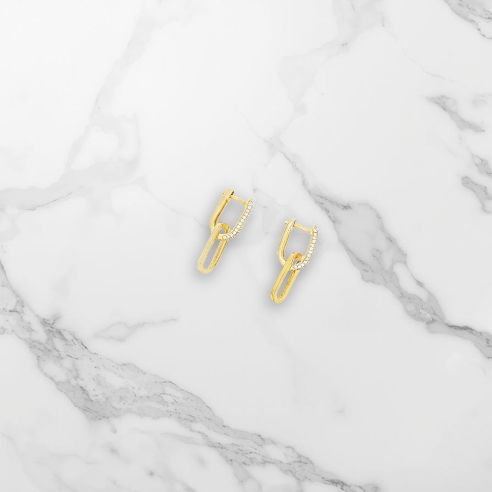 Paire de boucle d'oreille zirconium posée sur du marbre blanc