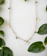 Collier quart vert avec des symbôles porte-bonheur entouré de feuilles vertes