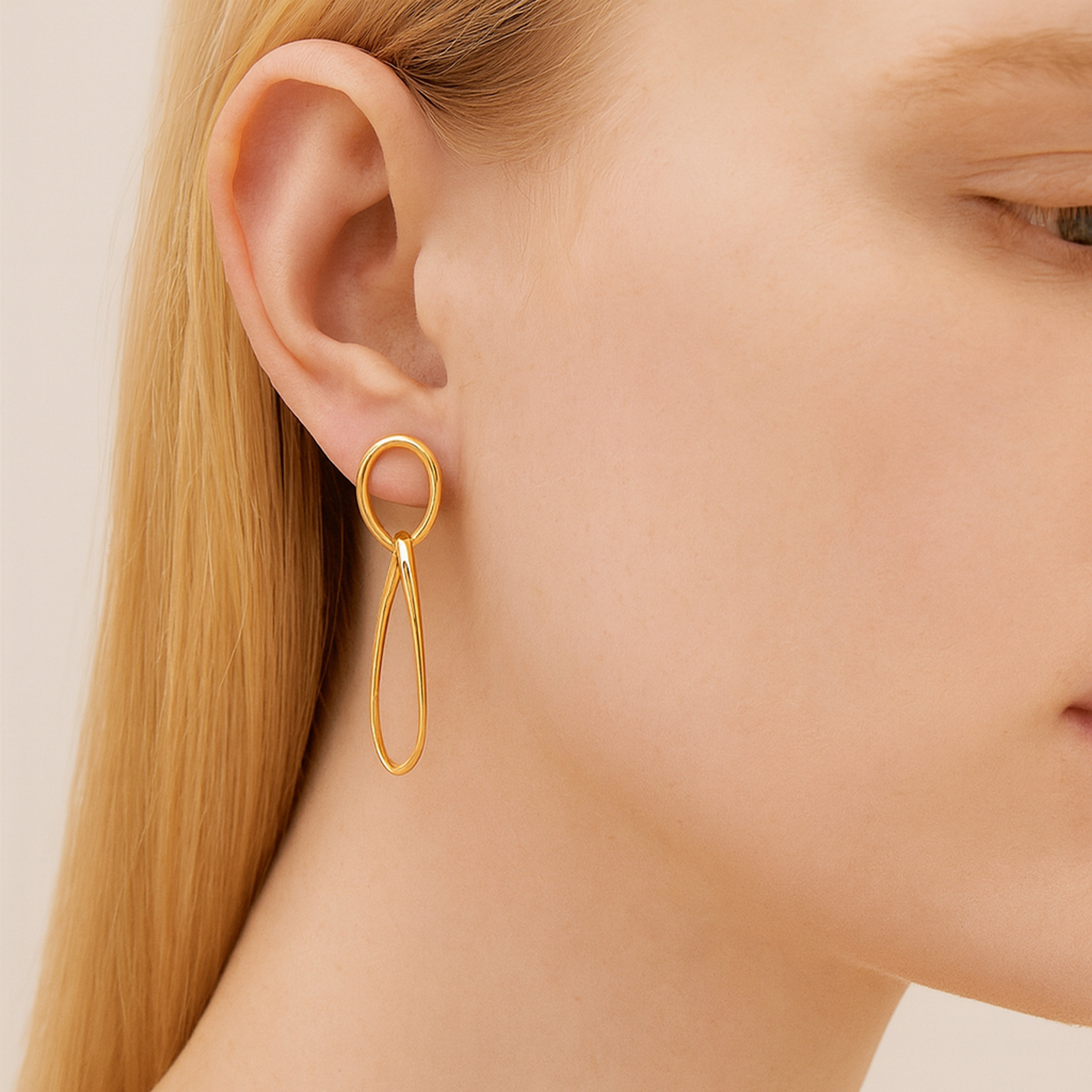 Femme porte des boucles d'oreilles pendantes ovales couleur or jaune