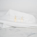 Boucles d'oreilles modulables serties de zircons posées sur un tissu blanc