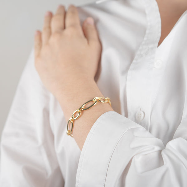 Bracelet gros maillons de couleur or jaune porté avec une chemise blanche