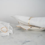 Bracelet longs maillons en argent couleur or jaune entourant un tissu blanc sur du marbre