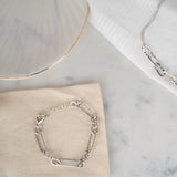 Bracelet deux maillons de couleur gris posé sur un tissu beige
