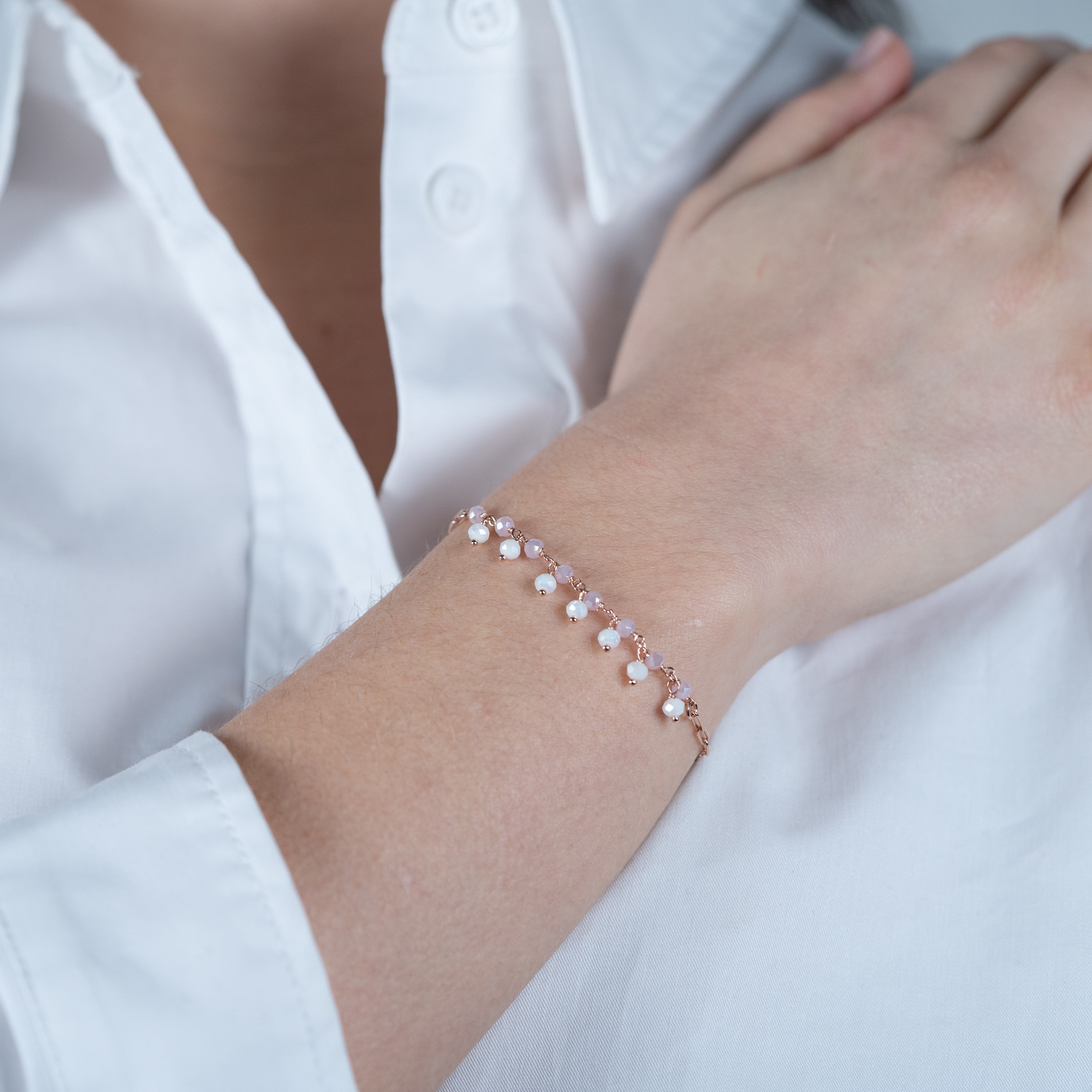 Bracelet couleur or rose serti de pierres blanches porté avec une chemise blanche