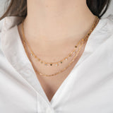 Collier de couleur or jaune serti de zircons porté avec une chemise blanche